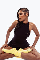 Woman in a black outfit with yellow accents on a white background
