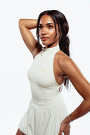 Woman wearing a white sleeveless dress on a plain background